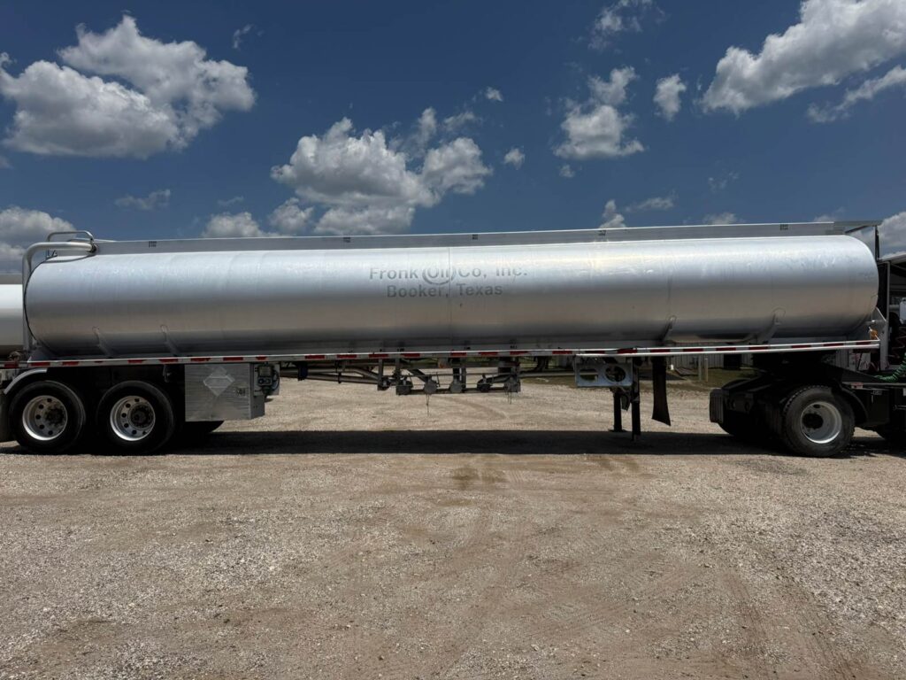 Large silver fuel tanker trailer parked outdoors under blue sky.